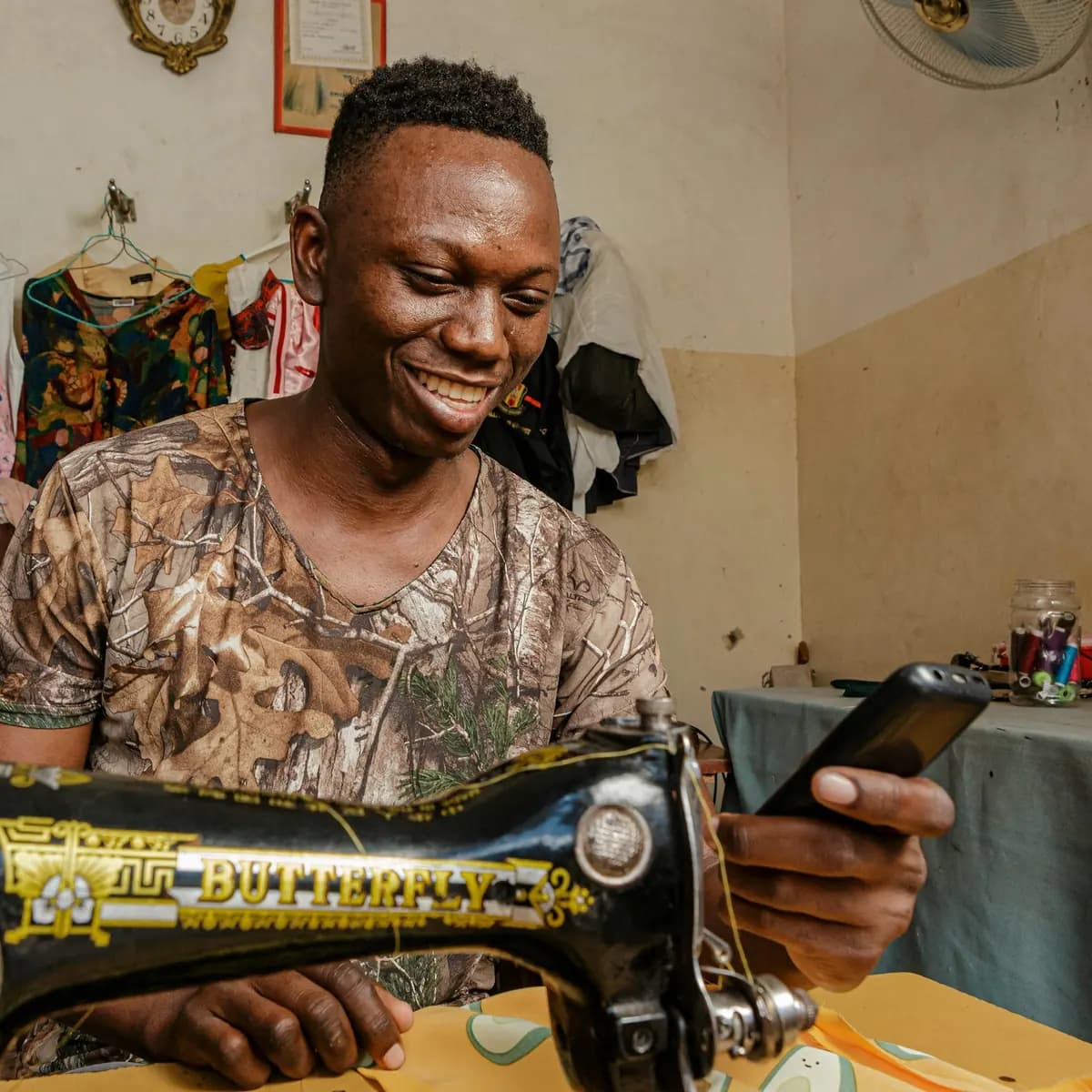 Fundi cherehani akitabasamu huku akitumia simu