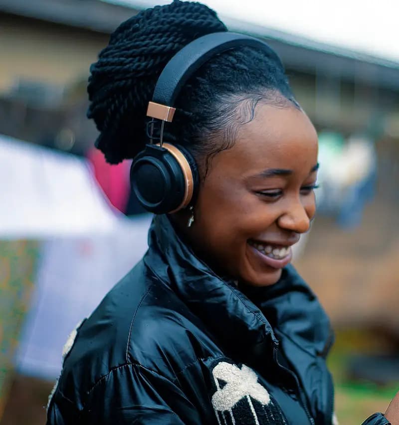 Mwanamke mwenye vipokea sauti akitabasamu akitazama simu yake