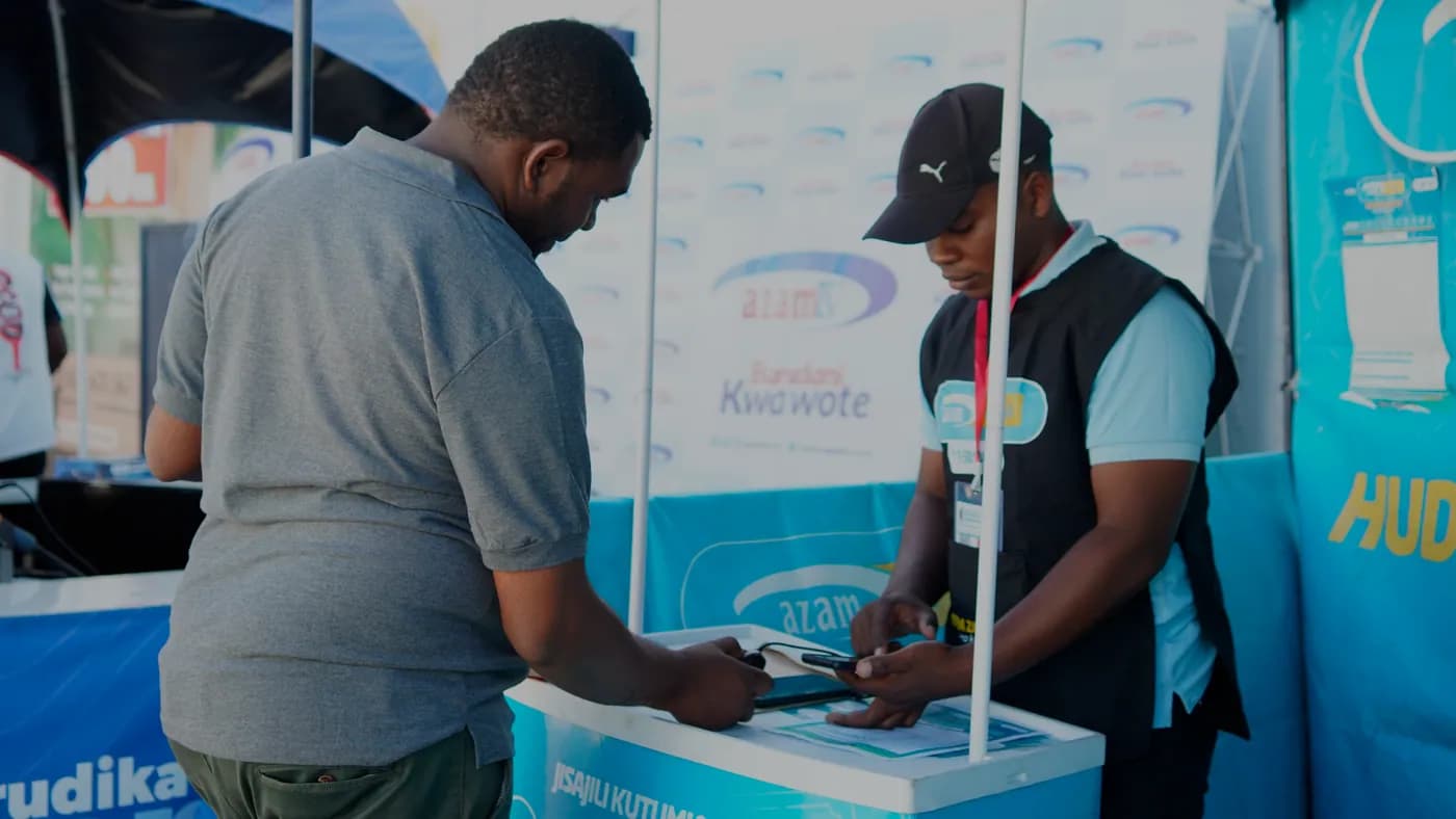Msajili wa AzamPesa akimsajili mteja kwenye meza ya AzamPesa