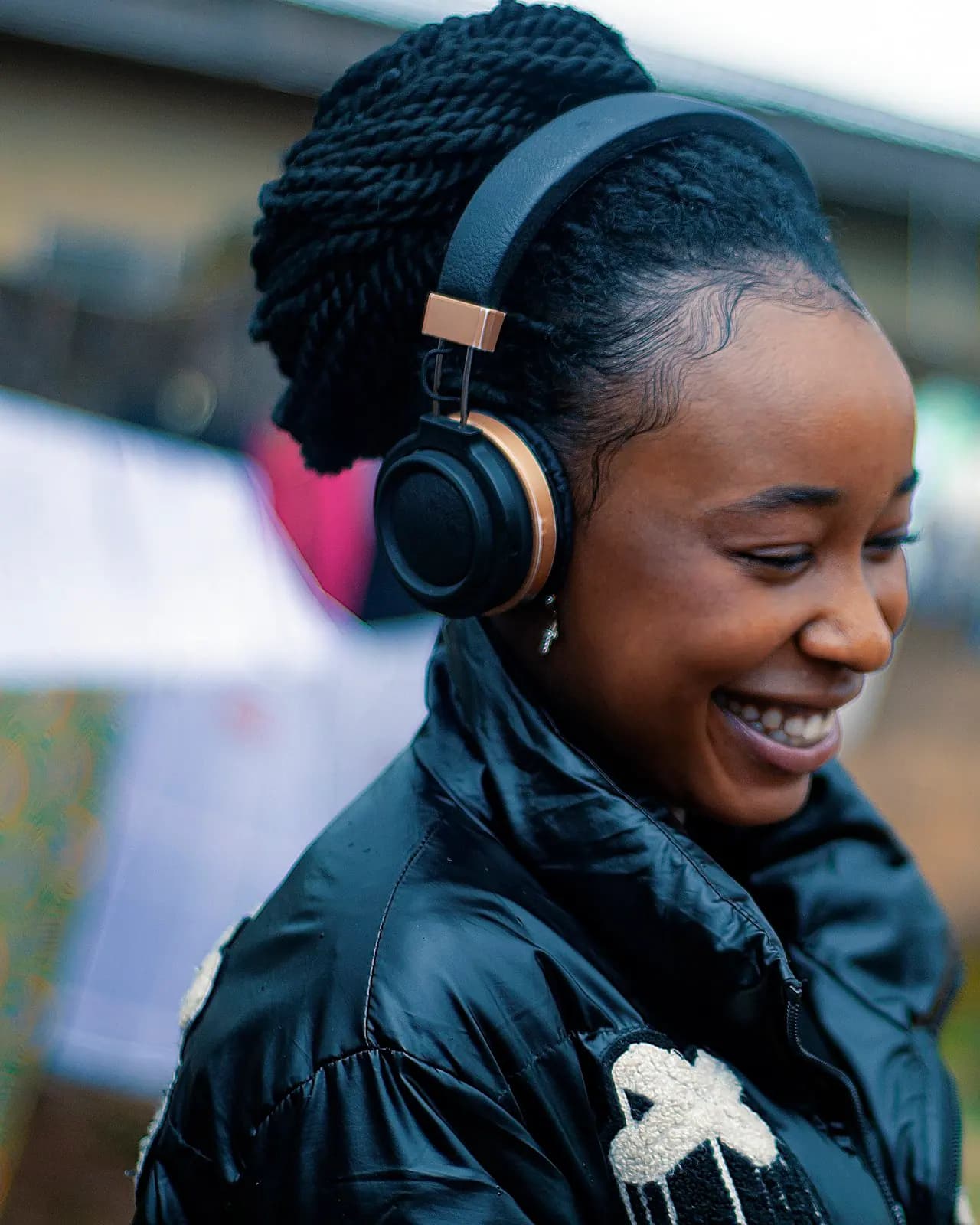 A young woman in headphones smiling at her phone