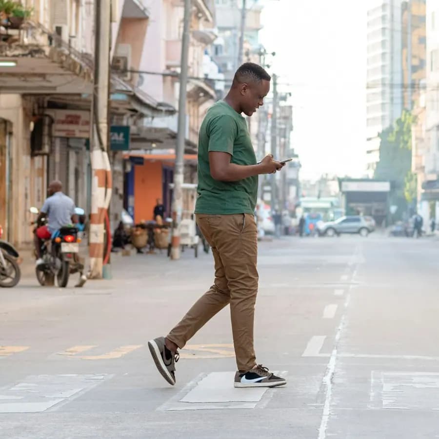 Mwanaume akivuka barabara jijini Dar es Salaam huku akitumia simu